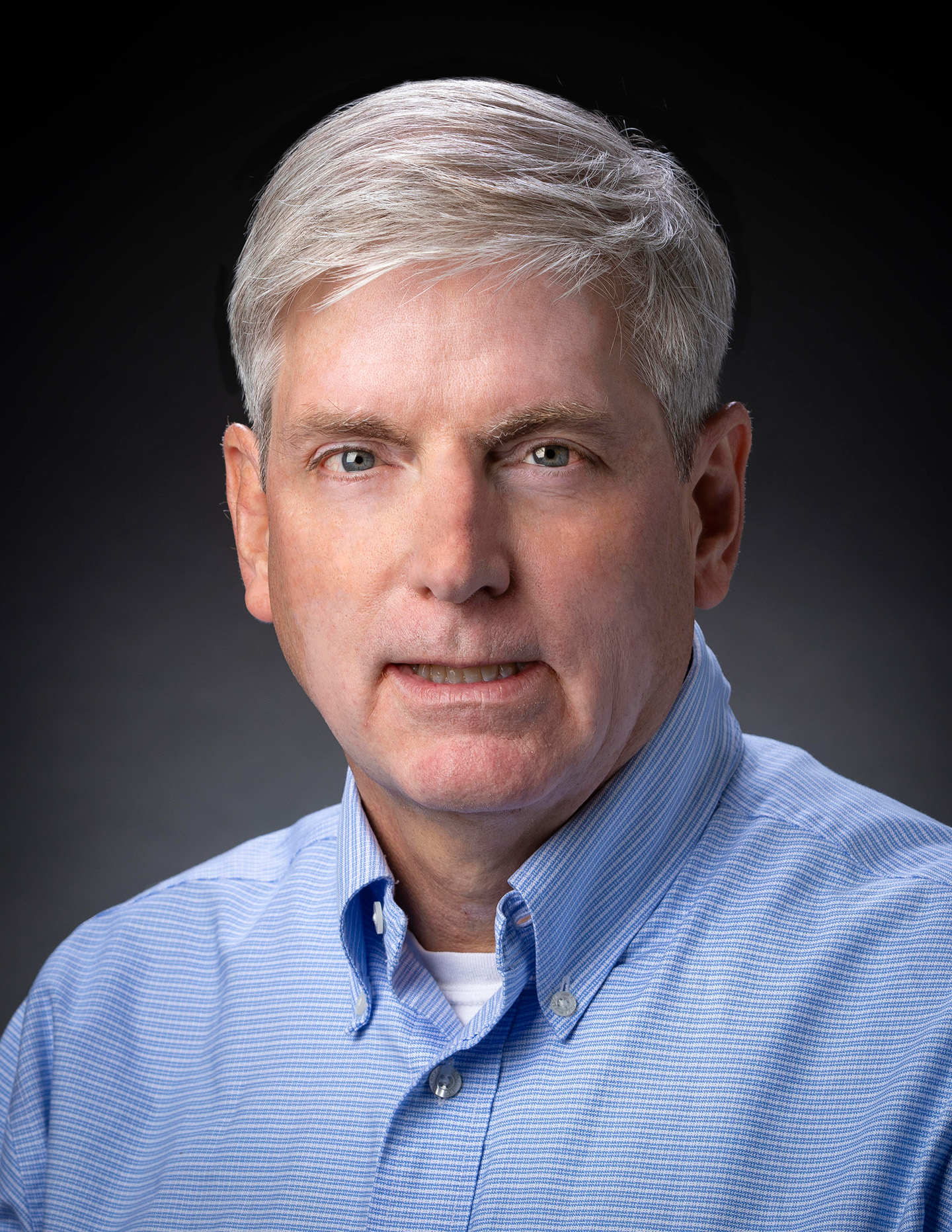 Head shot photo of Ed Reynolds, in a blue collared shirt