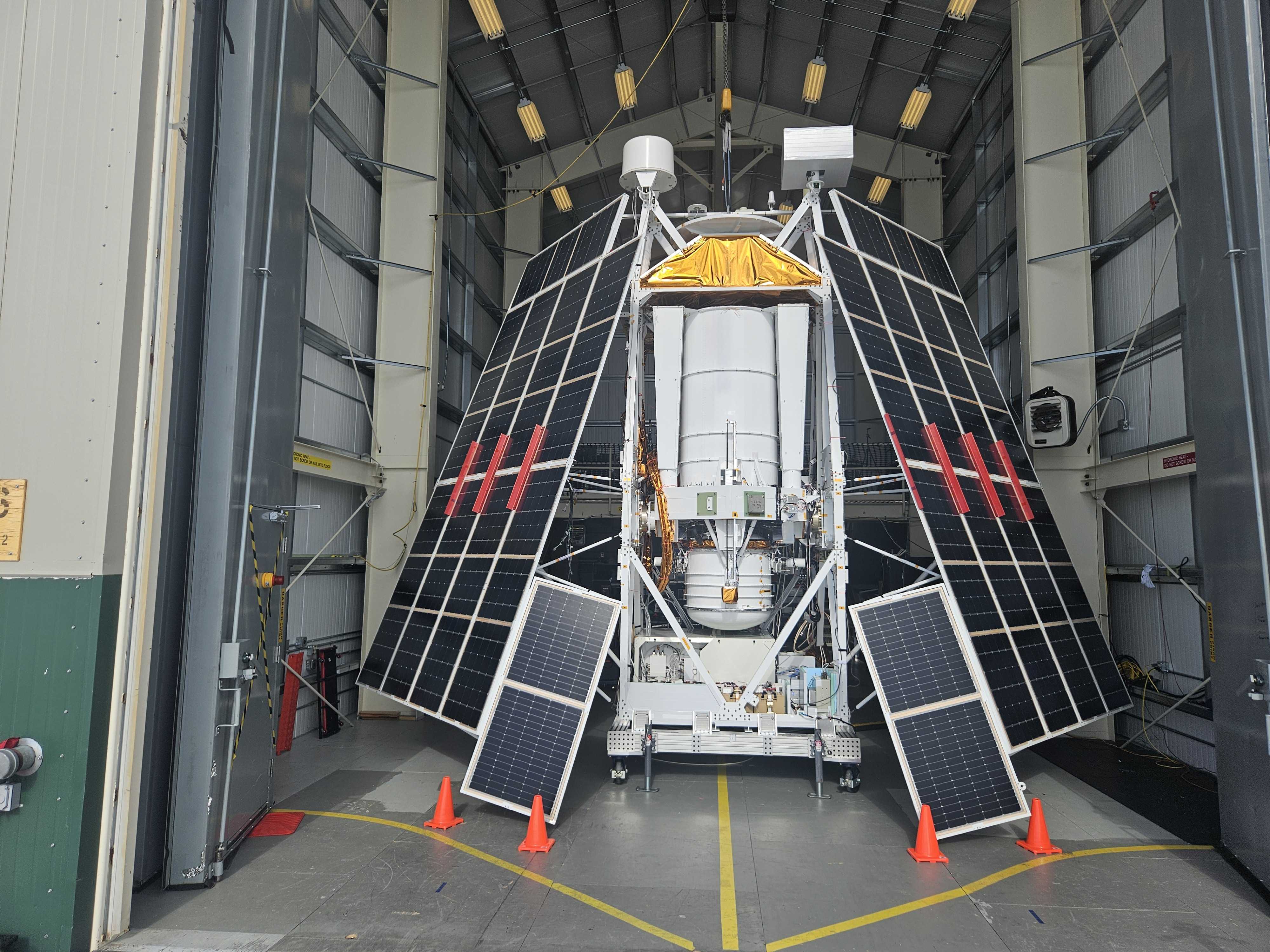 A photo of the GUSTO telescope and gondola shows it inside a hangar with solar arrays mounted. Four orange traffic cones sit in front of the structure