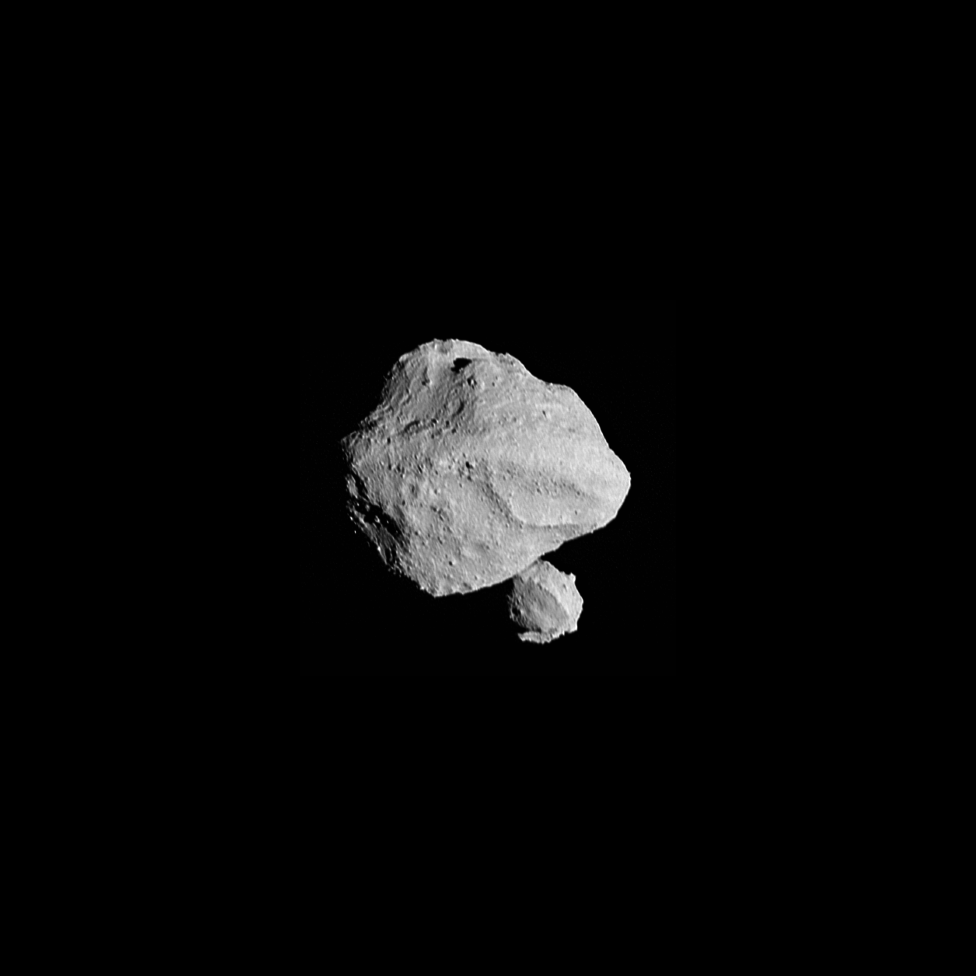 Photo of a double-coned asteroid, Dinkinesh, in space with a smaller satellite asteroid on the bottom right