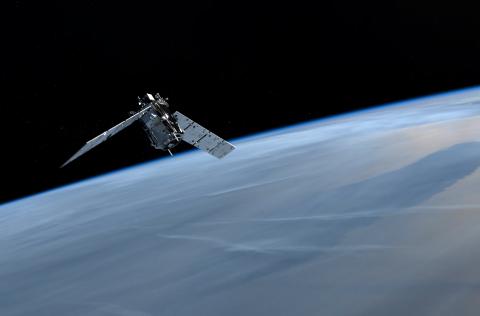 A spacecraft flies high above the blue and cloud-covered Earth