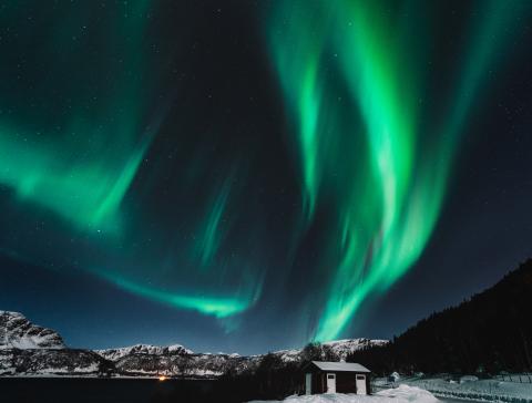 Image of green auroras above snow-capped mountains 