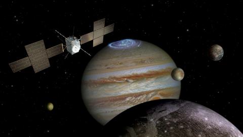 The European Space Agenc's JUICE spacecraft flies in the Jovian system, with Jupiter and its northern aurora, Io, Europa and Callisto visible in background, and Ganymede in the foreground
