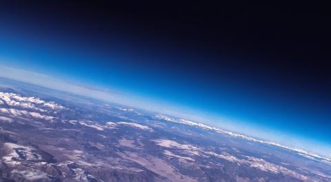 An image of a part of Earth from space, with a blue atmosphere surrounding it and mountains on the surface visible